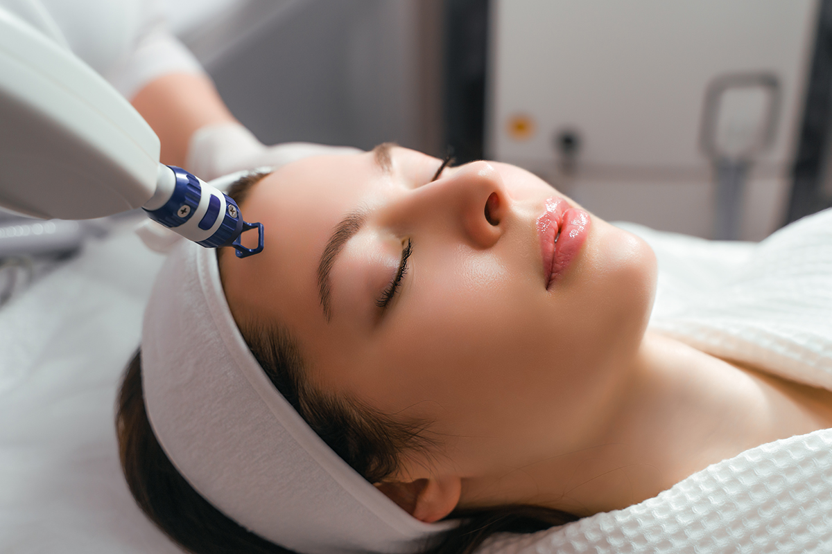 Woman receiving facial laser treatment while lying down comfortably.
