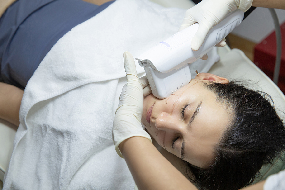 Woman receiving Ultherapy treatment on her face in an aesthetic clinic.