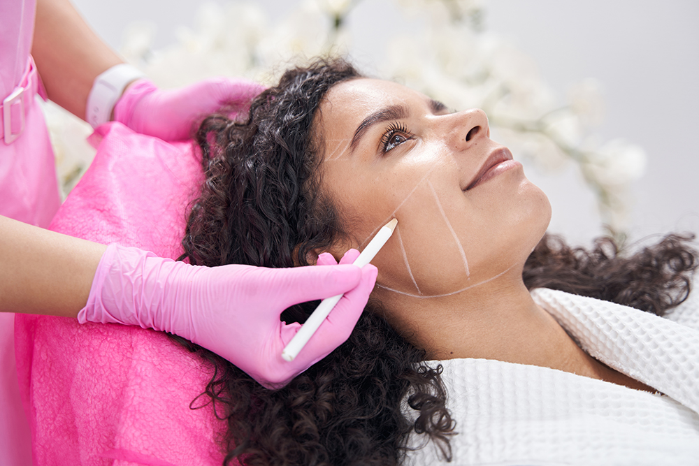 A doctor places marks on a patient's cheek to assist with cosmetic treatment planning.