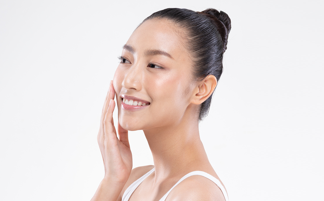 Side profile of a woman touching her face with smooth, glowing skin after Rejuran skin booster treatment