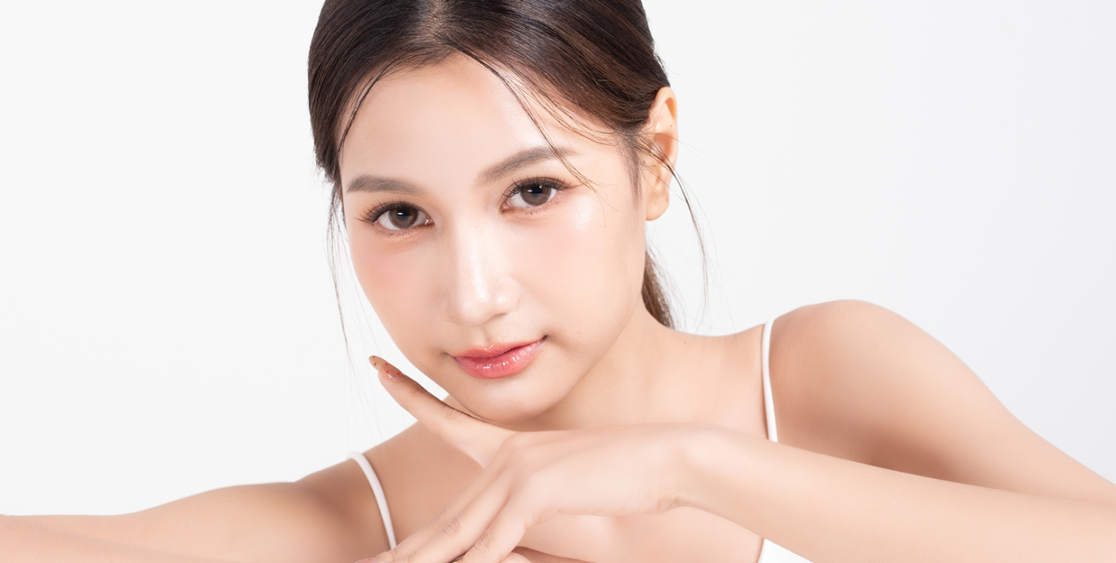 Asian woman resting her chin on her hands showcasing clear, radiant skin