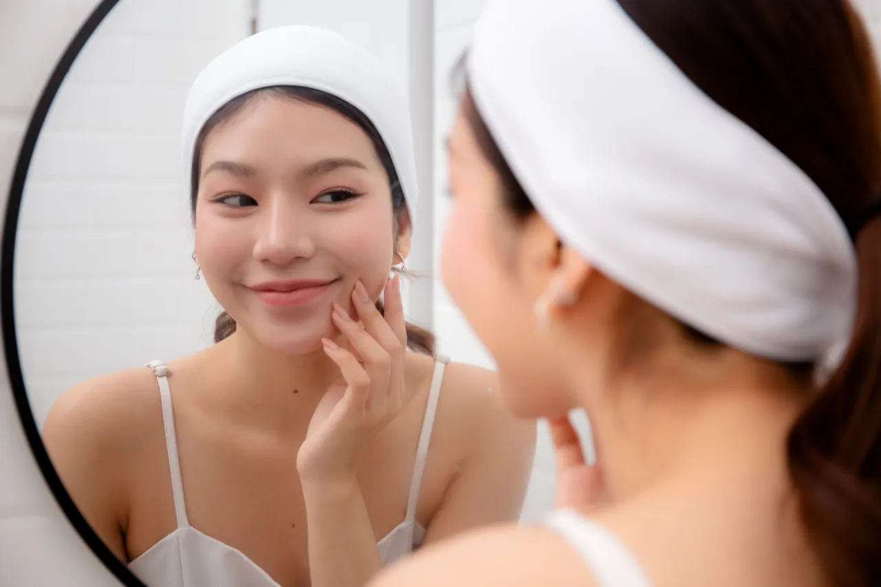 A smiling woman looking at herself in the mirror