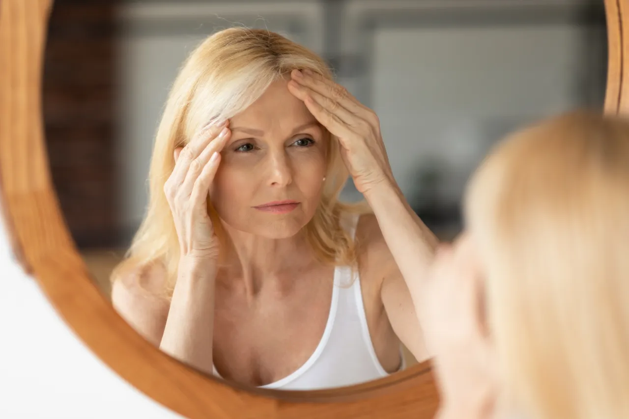 A senior woman looking at her skin in the mirror