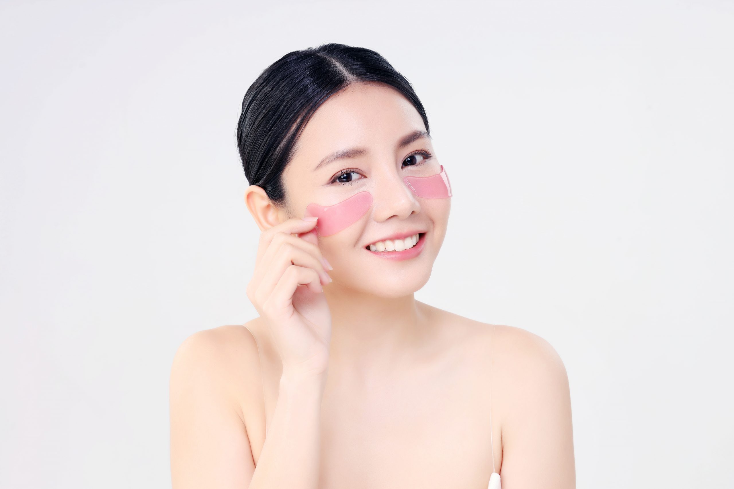 Cosmetic Eye Mask. Close Up Beauty Face Asian Woman With Fresh Clean Skin Using Eye Pad. Eye Care Treatment. Isolated on white. Beauty And Skin Care Concept.